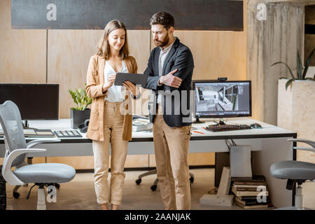 Zwei kreative Mitarbeiter als Interior Designer arbeiten mit digitalen Tablet, gemeinsam im modernen Büro von Architekturbüro Stockfoto
