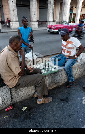 Die einheimischen Männer sitzen auf Marmorsitzen und spielen auf dem Passeo del Prado, einem langen Boulevard in Havanna, Kuba, eine Partie Schach. Der Boulevard, gesäumt mit Bronze Stockfoto