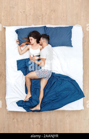 Bedtime. Junger Mann, Bein auf Frau umarmen schlafend auf dem Bett Top View friedliche Stockfoto