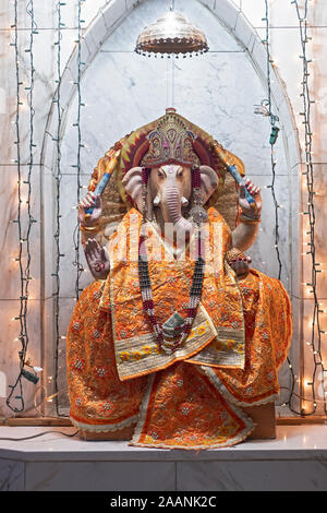 Eine Statue des hinduistischen Gottes Ganesh in orangefarbene Gewänder an der Satya Narayan Mandir in Queens, New York City gekleidet. Stockfoto