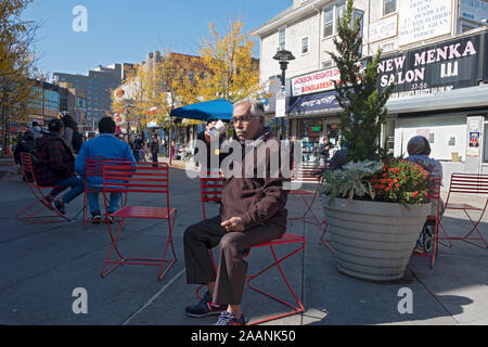 Ein Mann (vermutlich ein Immigrant) Tee trinken in Vielfalt Plaza in Jackson Heights an einem kühlen Herbst Tag. In Queens, New York City. Stockfoto