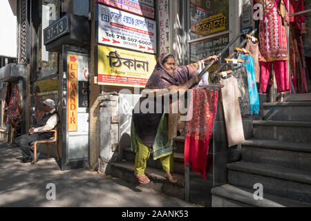 Eine ältere islamischen Frau geht nach unten ta Treppe mit Schwierigkeiten mit beiden Händen, um Unterstützung zu erhalten. In Jackson Heights, Queens, New York City. Stockfoto