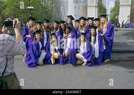 Eine vielfältige Gruppe von Frauen posieren für ein Foto in Ihrer graduation Caps & Kleider vor dem Brunnen im Washington Square Park in Greenwich Village, NY Stockfoto