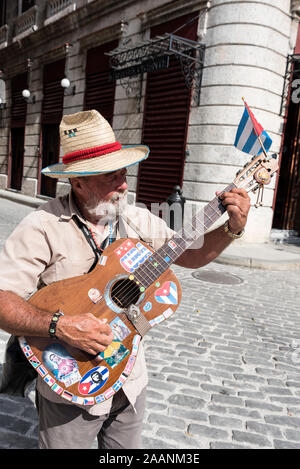 Ein kubanischer Straßenmusiker spielt seine Gitarre vor Touristen auf der Plaza San Francisco in der Altstadt von Havanna in Kuba. Stockfoto