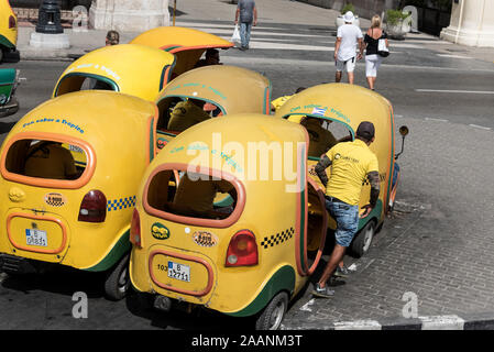 Eine kleine Flotte gelber Cocotaxi auf einen Parkplatz in Havannas Altstadt ( Habana Vieja) in Kuba. Das Cocotaxi, ein vertrauter Anblick in den Straßen von Ha Stockfoto