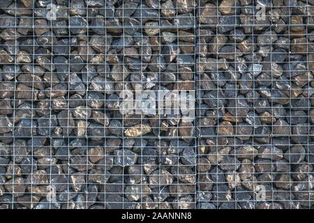 Kabel Gabione Rock Zaun. Käfig aus Metall gefüllt mit Steinen. Textur Hintergrund des rock Zaun mit Käfig. Schön beleuchtet nützliche Hintergrund. Stockfoto