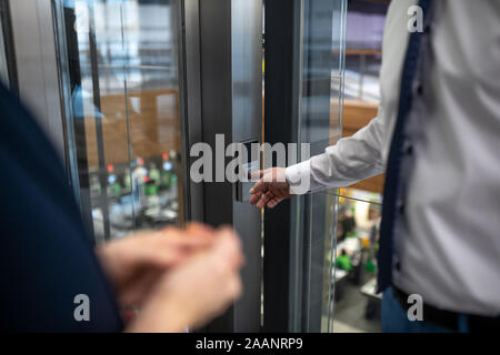 Nahaufnahme der Geschäftsmann den Knopf beim Warten auf den Fahrstuhl Stockfoto