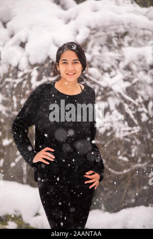 Biracial jugendlich Mädchen oder junge Frau im Freien im Winter genießen Sie frischen Schnee fallen Stockfoto