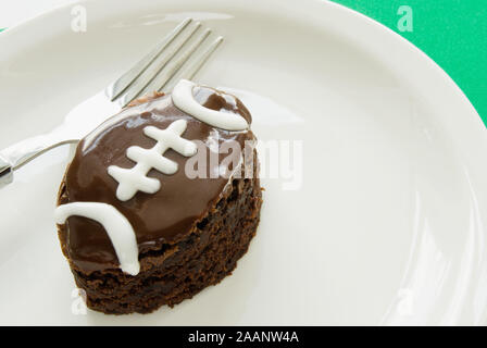 Hausgemachte Fußball geformte double Fudge Chocolate iced Brownie mit weißer Paspel auf einem Teller serviert. Stockfoto