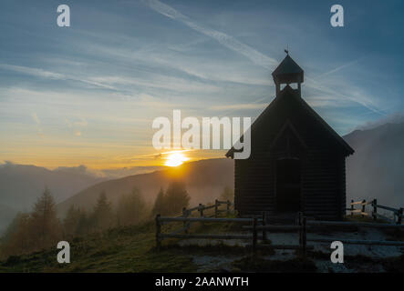 Sonnenuntergang an einem nebligen Abend mit Blick auf das Tal und die CHIESETTA Alpina chappel an der Valles Pass in den italienischen Dolomiten Stockfoto