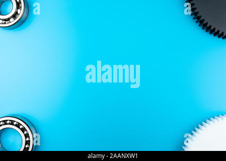 Kugellager und schwarzen und weißen Kunststoff Zahnrad liegen auf einem blauen Hintergrund mit Kopie Raum in der Mitte. Flache Ansicht von oben. Stockfoto