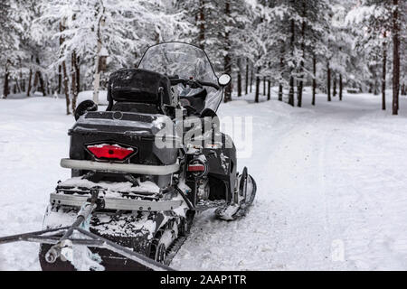 Finnland, Inari - Januar 2019: Schwarz Frost überzogen Schneemobil auf einem verschneiten Wald Trail Stockfoto