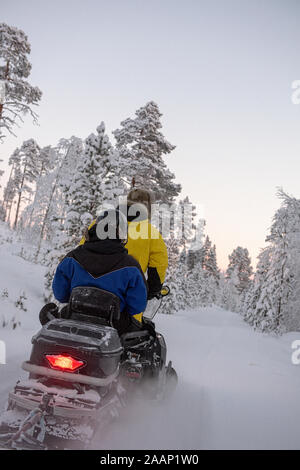 Finnland, Inari - Januar 2019: 2 Personen reiten auf einem Schneemobil durch die Wildnis von Lappland Stockfoto