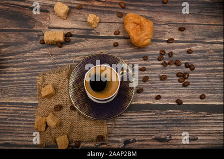 Tasse Kaffee, Croissants, brauner Zucker und Kaffee Bohnen auf Holz- Hintergrund. Nahaufnahme Stockfoto