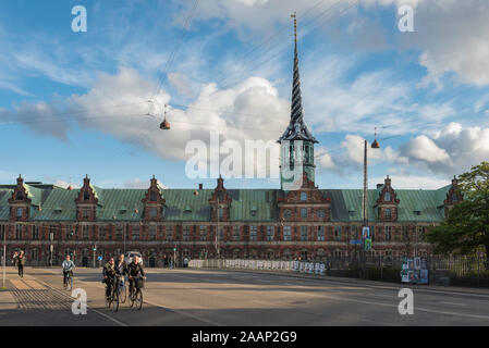 Kopenhagen, Dänemark, Blick auf die Radfahrer Überqueren der Brücke auf Slotsholmen Borsbroen mit der Stadt Bourse Gebäude in der Ferne, Kopenhagen, Dänemark. Stockfoto