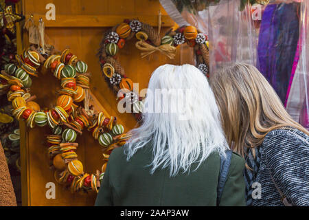 Frauen an duftende Gewürze Obst Produkte Suchen auf Abschaltdruck an der Winchester Weihnachtsmarkt, Winchester, Hampshire, UK im Dezember Stockfoto