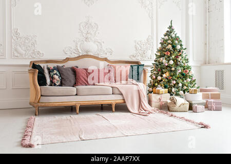 Weihnachtsbaum umgeben von giftboxes steht in der Nähe der Couch im Wohnzimmer. Stockfoto