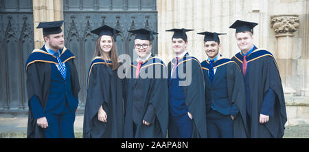 Eine Gruppe von Happy New York St John University Absolventen tragen Kleider und Hüte Mortarboard auf ihrer Abschlussfeier an der York Minster Stockfoto