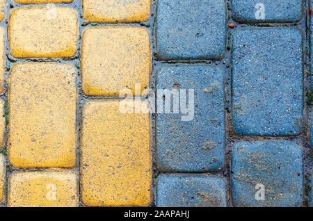 Gelb und Blau Kopfsteinpflaster Bürgersteig Textur. steinmetzkunst Bodenbelag Nahaufnahme. Blick von oben auf die vertikale Nass grungy Hintergrund Stockfoto