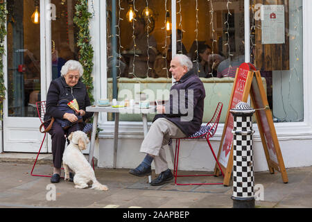 Paar Senioren Fütterung Hund während der Wartezeit Bill an drei Joes, tolle Münster St, Winchester, Hampshire, UK zu zahlen im Dezember Stockfoto