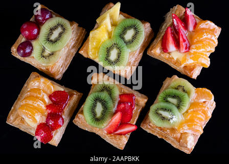 Blätterteig mit Mandarine, Kiwi und Erdbeeren Obst auf schwarzem Hintergrund gesehen von oben Stockfoto