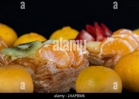 Blätterteig mit Tangerine Obst auf schwarzem Hintergrund Stockfoto