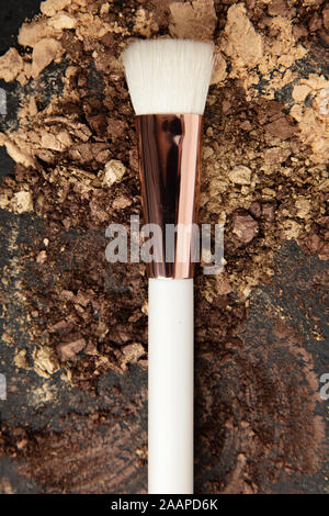 Weißes make up Pinsel und Braun und Gold Lidschatten auf flachen Stein angeordnet Stockfoto