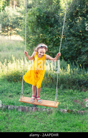 Schöne jugendlich Mädchen stehen auf Schwingen am Sommertag, Glückliche Kindheit Konzept Stockfoto