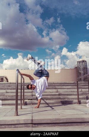 Junge aktive Tänzer steht auf einem Arm, sport Mann, in der Stadt im Sommer, Break-Tänzer, Hip-Hop, Modern Dance Stil, Jugend Lifestyle. Straße Stockfoto