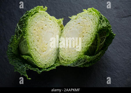 Eine Halbierung der Britischen Wirsing gekauft von einem Supermarkt in Großbritannien. Auf dunklem Schiefer Hintergrund fotografiert. England UK GB Stockfoto