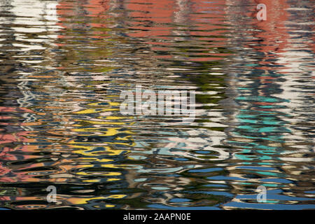 Spiegelungen im Wasser der Bunte Häuser auf einem Hügel mit Blick auf den Hafen von Brixham. Devon England UK GB Stockfoto