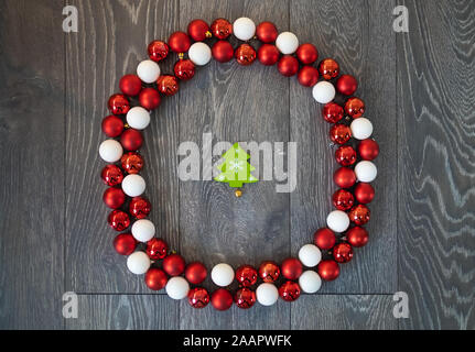 Rote und weiße Christbaumkugeln platziert im Kreis wie ein Kranz, mit einem grünen Baum geformt Ornament in der Mitte Stockfoto