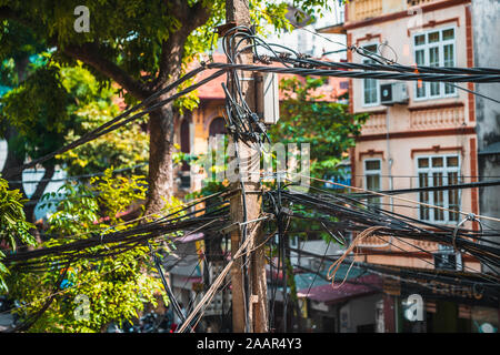 Unordentliche Kabelsalat rund um einen Strommast in Hanoi, Vietnam. Nahaufnahme zeigt die Verwirrung und Unordnung, die Drähte darstellen Stockfoto