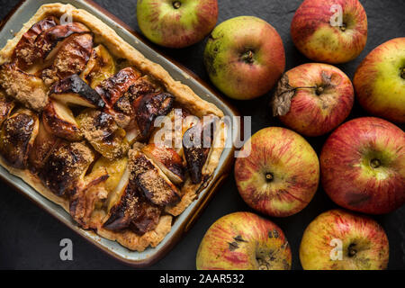 Ein Apfelkuchen mit mürbteig Gebäck, Zitronensaft, braunem Zucker und Äpfel, die freundlicherweise außerhalb eines Hauses mit einem Obstgarten gelassen wurde und angesichts der Awa Stockfoto