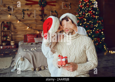 Paar gibt, präsentiert in einem Raum mit einem Weihnachtsbaum. Stockfoto