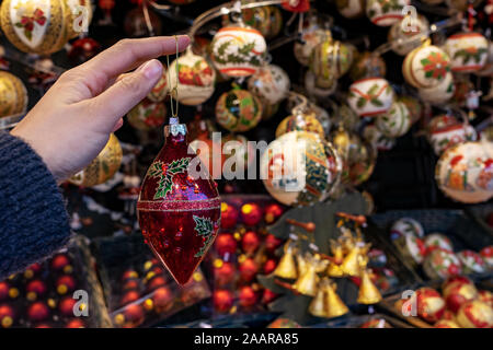 Frau mit hängenden Christmas ornament Dekoration mit Kiosk stehen auf einem winter Markt Hintergrund Stockfoto