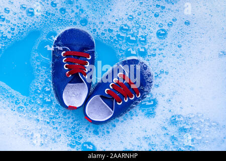 Genießen Sie Baby Schuhe Baby Waschmittel Wasser Auflösung vor dem Waschen. Wäscheservice Konzept, Ansicht von oben Stockfoto