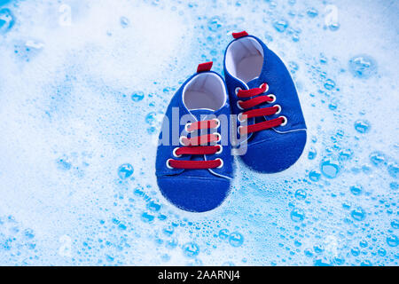 Genießen Sie Baby Schuhe Baby Waschmittel Wasser Auflösung vor dem Waschen. Wäscheservice Konzept, Ansicht von oben Stockfoto