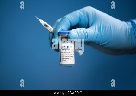 Behandschuhte hand mit humanem Normalinsulin Flasche und Spritze. Stockfoto