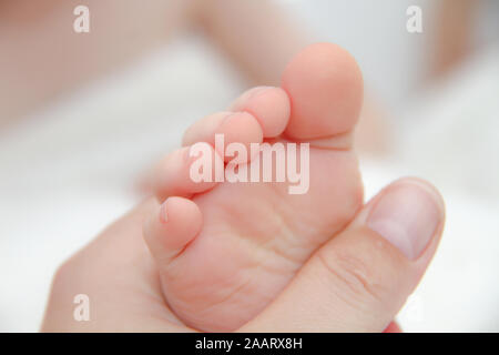 Mutter hält Füße Ihres kleinen Sohnes. Winzige Beine in der Hand der Frau. Stockfoto