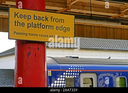 Zurück von der Bahnsteigkante, gelbes Schild, vorbeifahrende Züge verursachen Luftverwirbelungen, auf der Plattform, Hochgeschwindigkeitszüge Stockfoto