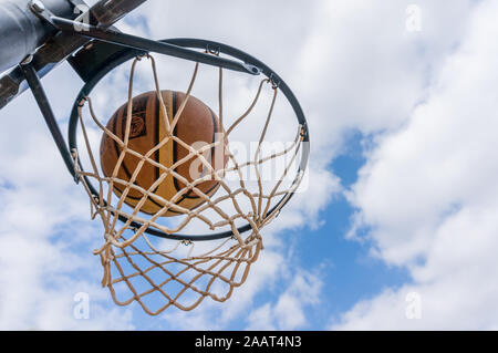 Basketball Ball geben Sie den Korb in einem Schießen im Freien swish mit blauem Himmel Stockfoto