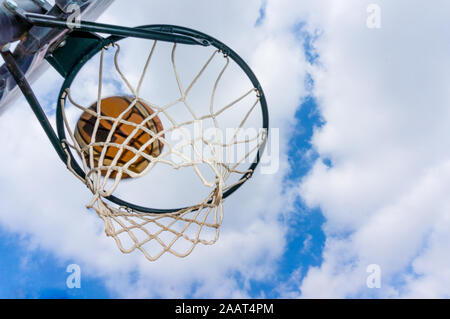 Basketball Ball geben Sie den Korb in einem Schießen im Freien swish mit blauem Himmel Stockfoto