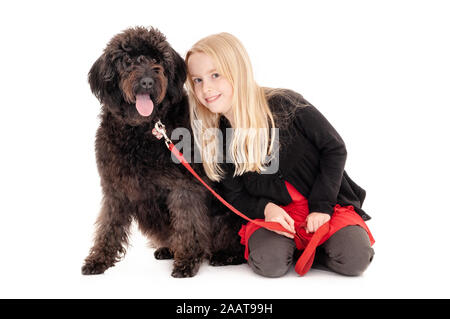 Glücklich, junge blonde Mädchen mit schwarzen Labradoodle auf einem roten Leine. Auf weissem studio Hintergrund isoliert Stockfoto