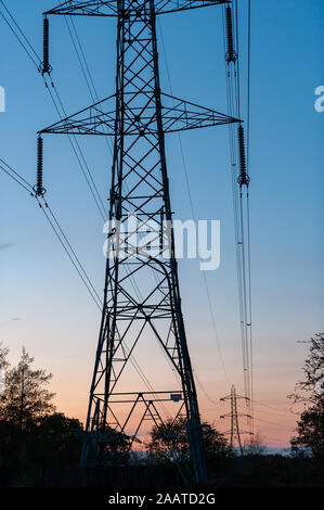 Strommasten mit blau und orange Himmel im Hintergrund kurz nach Sonnenuntergang Stockfoto