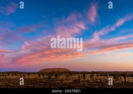 Uluru, auch Ayers Rock genannt, bei Sonnenuntergang mit interessante Wolkenformationen über. Northern Territory, Australien. Stockfoto