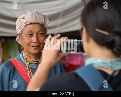 Japanische portrait Fotograf verwendet Ihr iPhone für einen schnellen Test shot eines älteren Thai Karen tribal Frau mit Betel - Mutter befleckten Lippen. Stockfoto