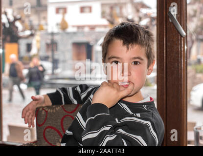 Porträt eines kleinen Jungen auf der Vorderseite des Fensters Stockfoto