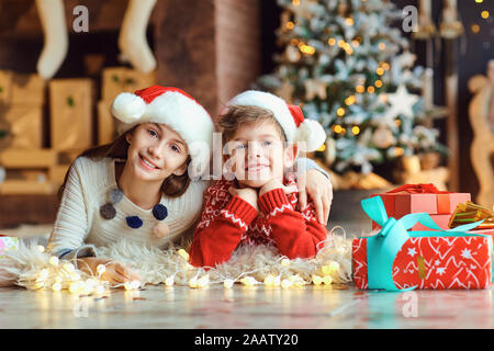 Kinder liegen auf dem Boden in Santa's Hüte auf Weihnachten. Stockfoto