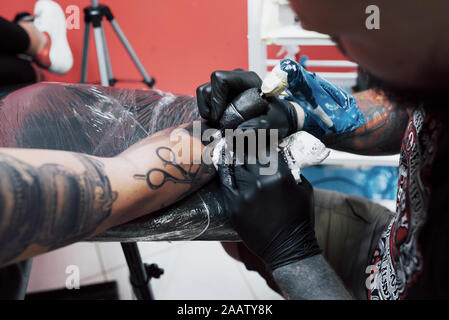 Close up Tattoo Maschine. Master in Schwarz sterile Handschuhe erstellen Bild an Hand mit Es im Salon Stockfoto